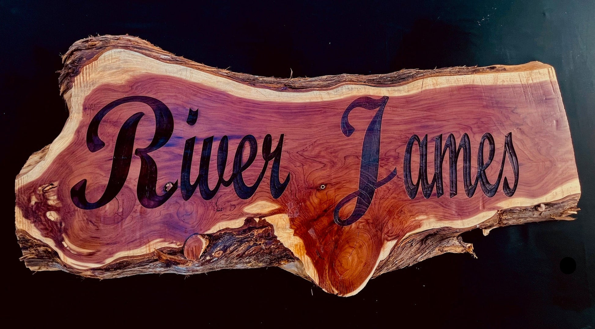 Live-edge cedar wood sign with deep laser-engraved name, showcasing natural grain and organic edges