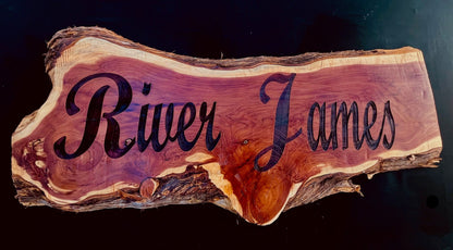 Live-edge cedar wood sign with deep laser-engraved name, showcasing natural grain and organic edges